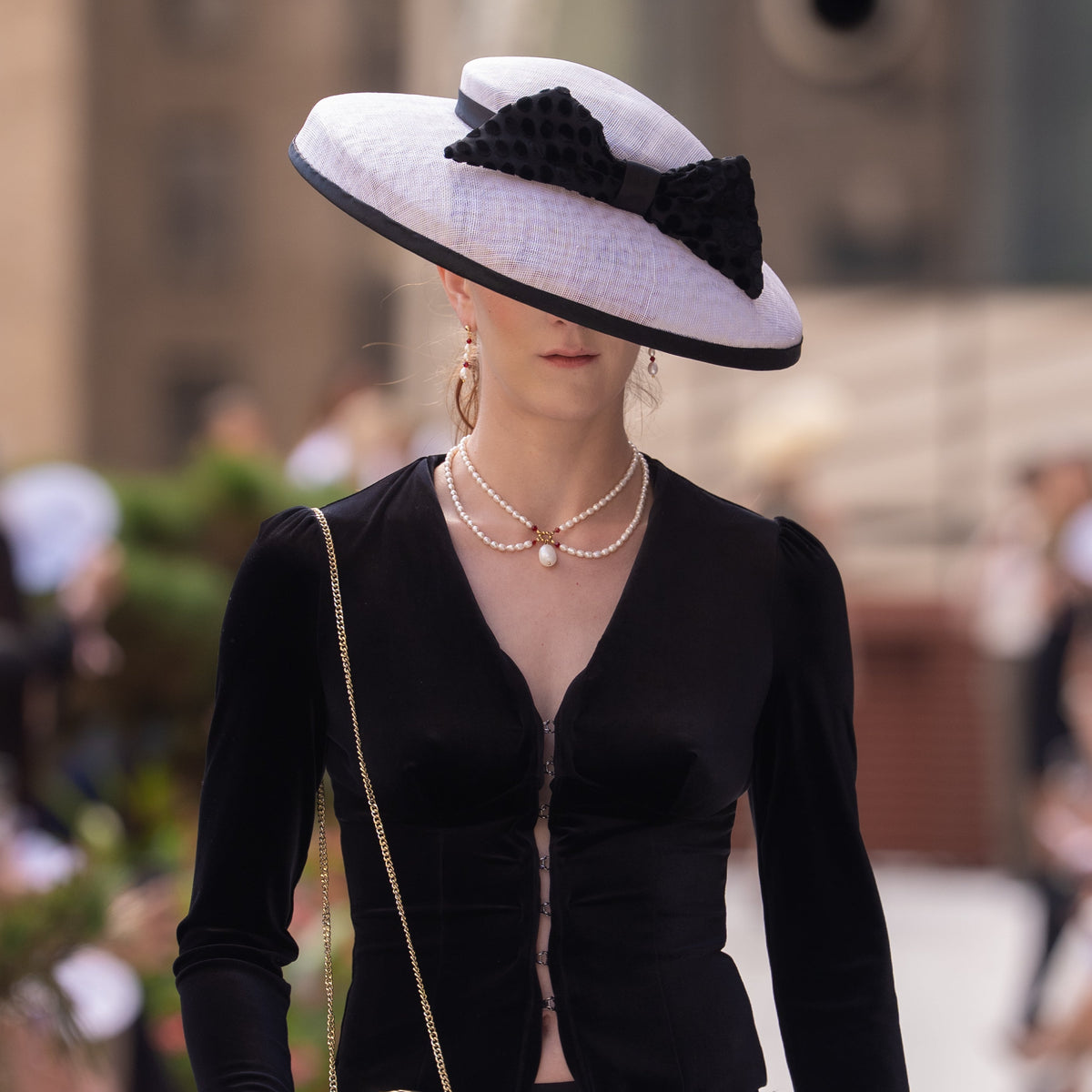 A romantic, vintage inspired necklace that features real freshwater pearls, red crystals, and 18k real gold plated beads. It is being worn by a model during New York Fashion Week. 