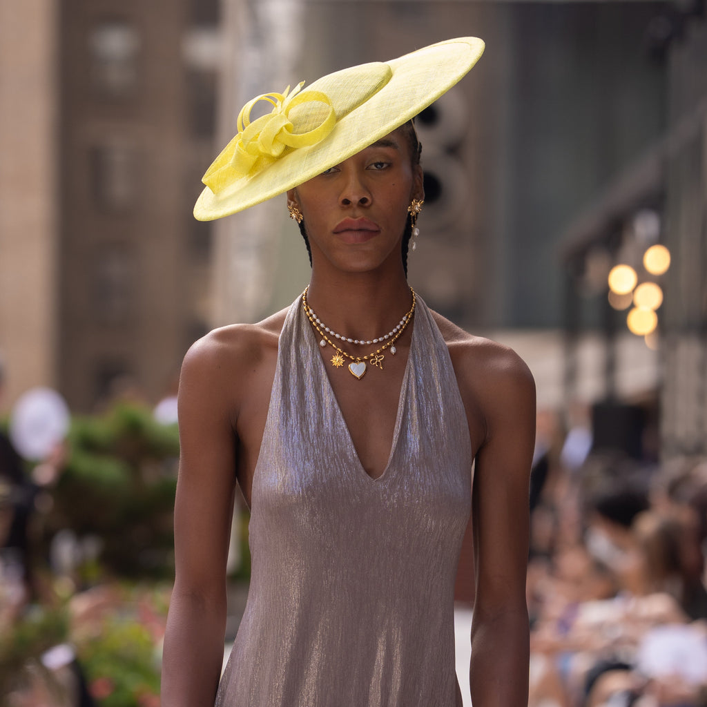 An 18k real gold plated charm necklace, worn by a model, during New York Fashion Week. The necklace features a mother of pearl locket and a string of real freshwater pearls. 